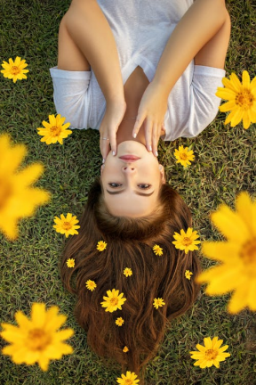 a woman lying on the grass with yellow flowers