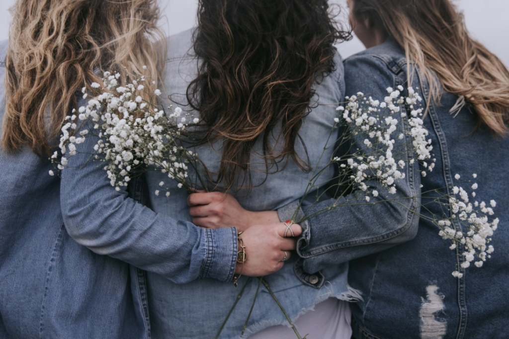 Three girls in denim showing different root lengths.